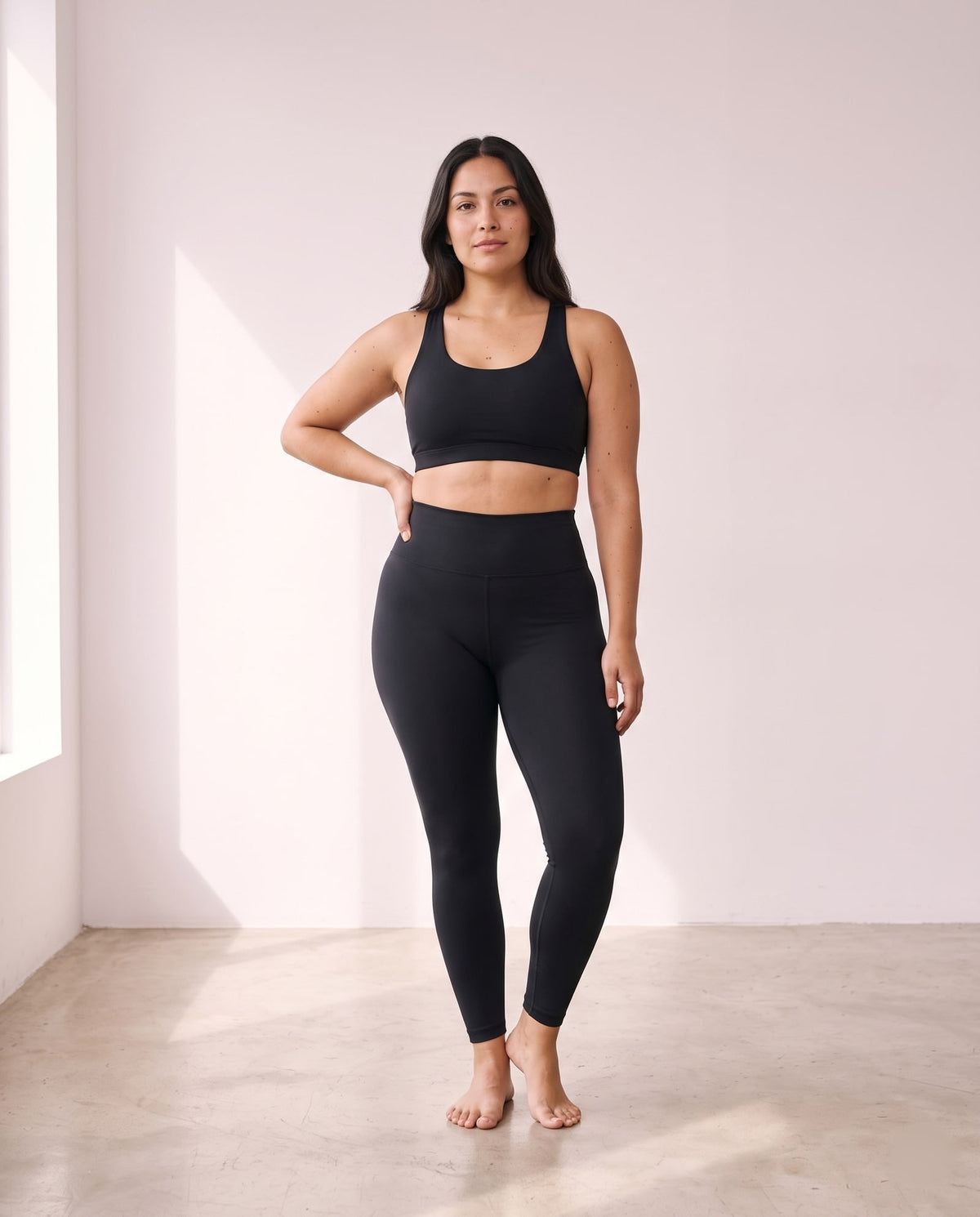 Mujer de pie con legging negro de talle alto y top deportivo negro